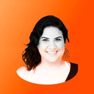 Uma mulher está sorrindo diante de um fundo laranja.