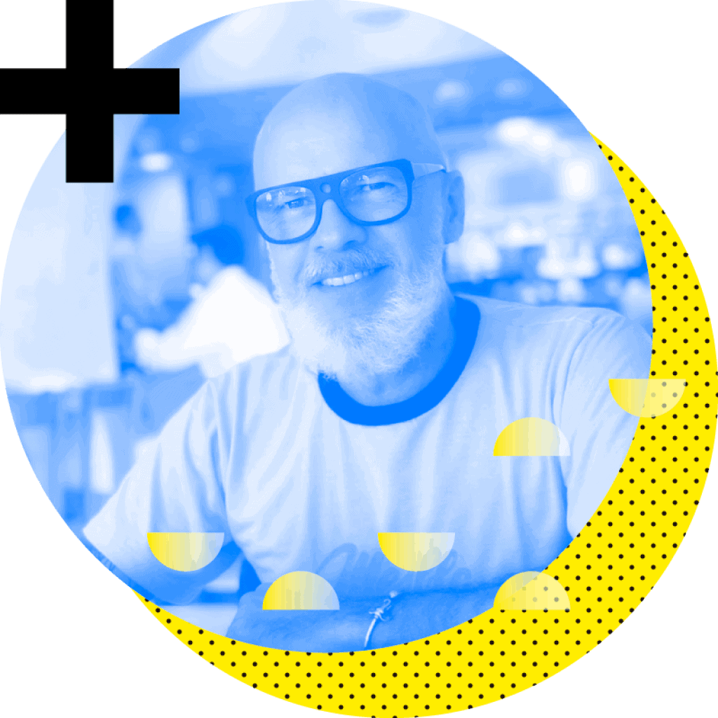 Um homem de óculos sorri diante de um círculo amarelo.