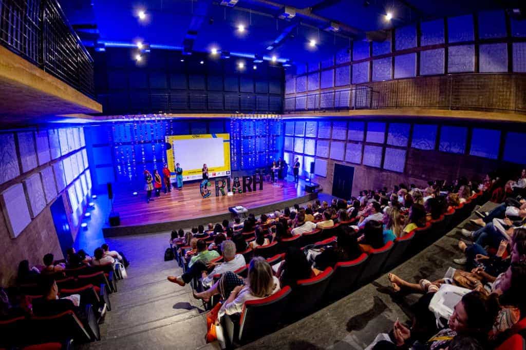 Uma placa em um auditório exibindo uma apresentação sobre consultoria de inovação.