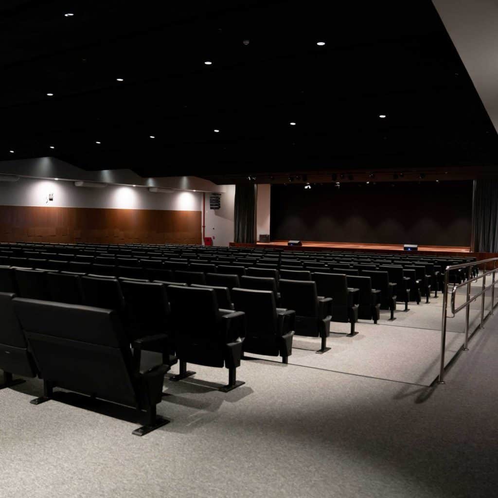 Um auditório com cadeiras pretas.