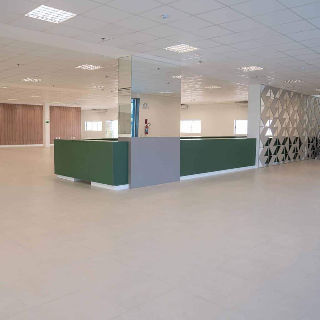 Um escritório vazio com paredes verdes e piso branco.
